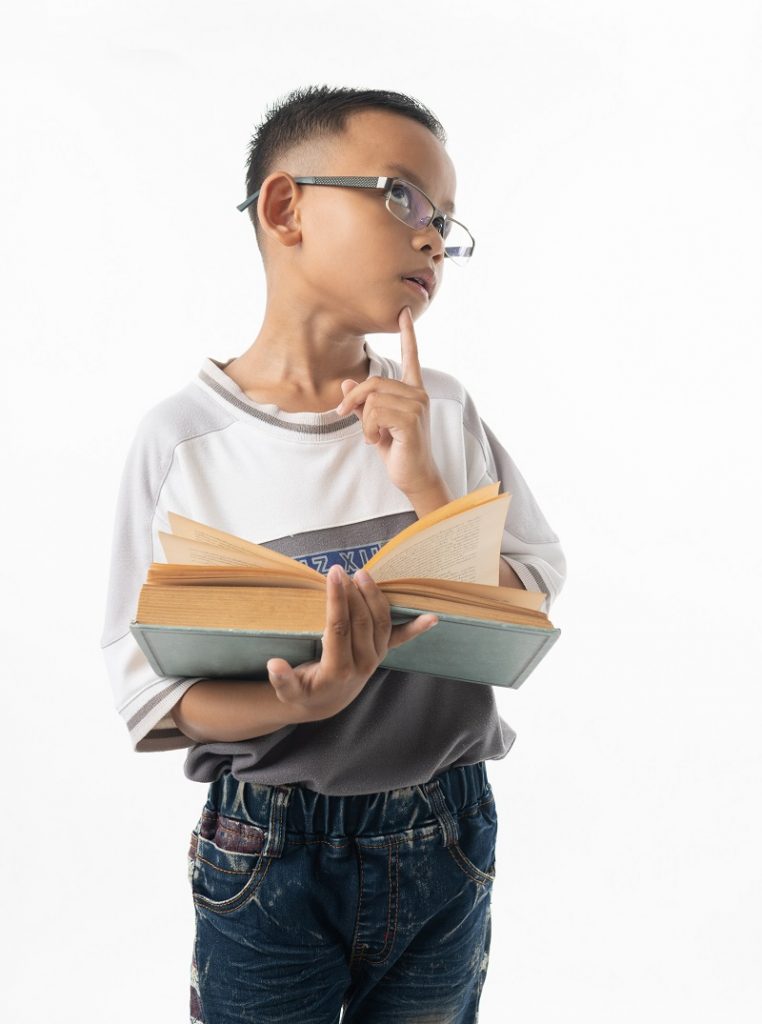 portrait of cute Asian boy student thinking and holding big book isolated on white background
