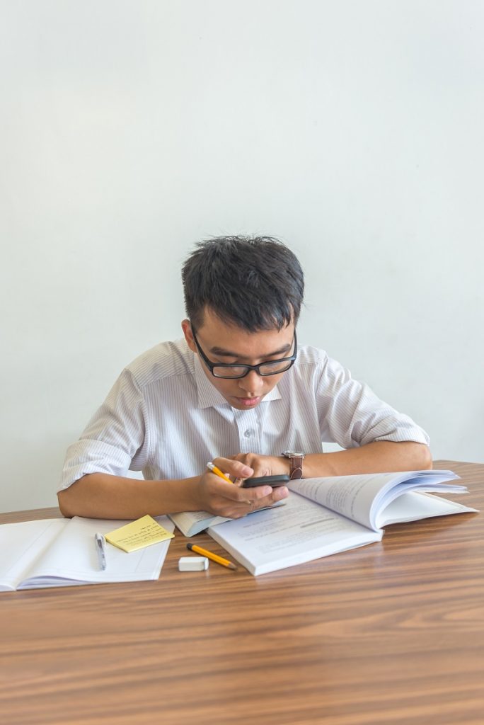 Vertical photo of young male student using smartphone